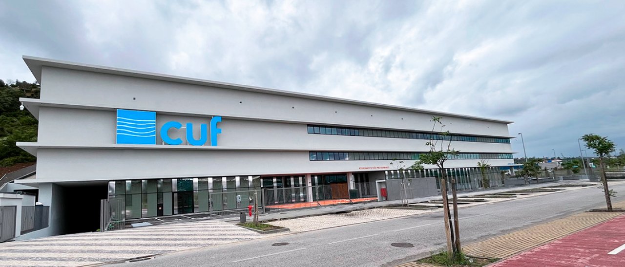 fachada do Hospital CUF Leiria com céu nublado e vista do parque de estacionamento exterior