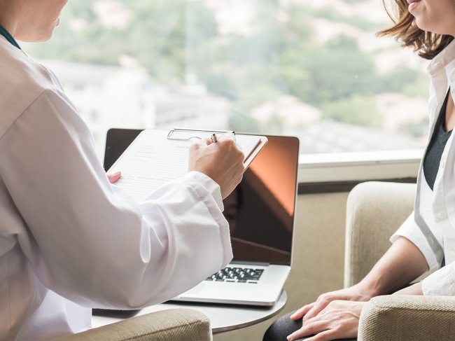 Mulher com cancro da mama em consulta faz perguntas ao médico