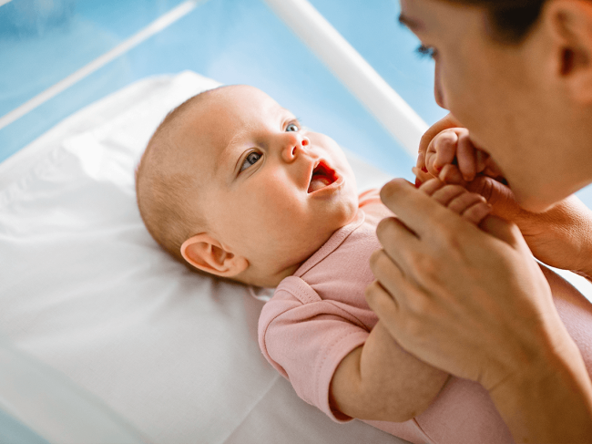 jovem mãe a beijar as mãos de bebé