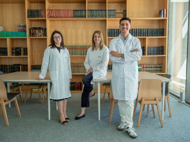 três medicos numa biblioteca a olhar de frente para a câmara