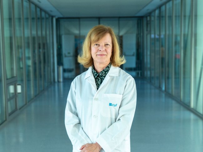 medica no corredor do hospital com mãos cruzadas à frente da barriga