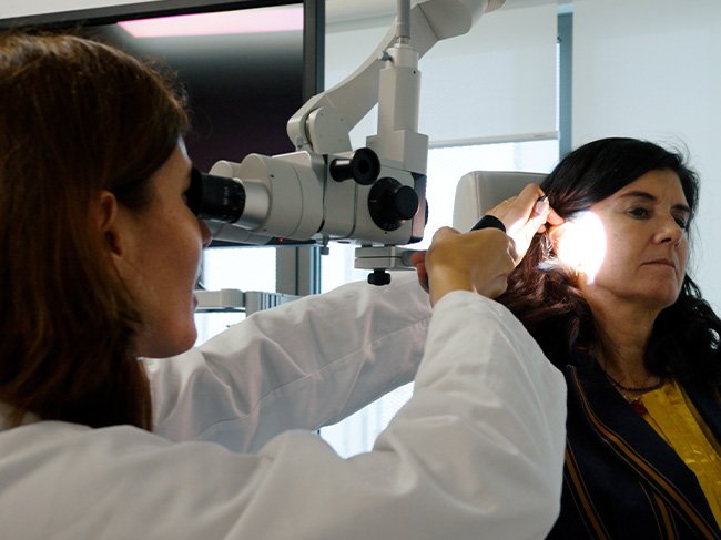 Médica faz exame ao ouvido após cirurgia de colocação de implante auditivo.