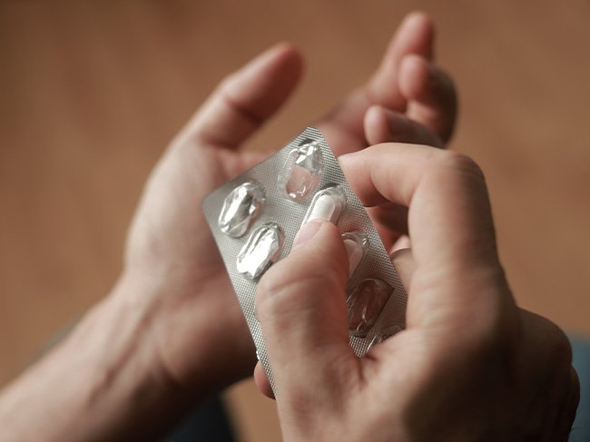 Pessoa toma um antibiótico em formato de comprimido.