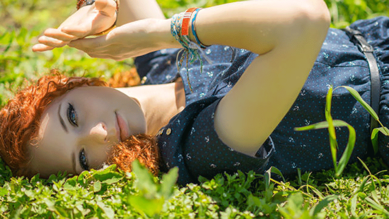 jovem tapa a cara com as mãos para proteger os olhos dos raios UV