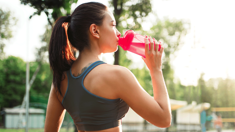 Mulher ingere bebidas desportivas durante o treino