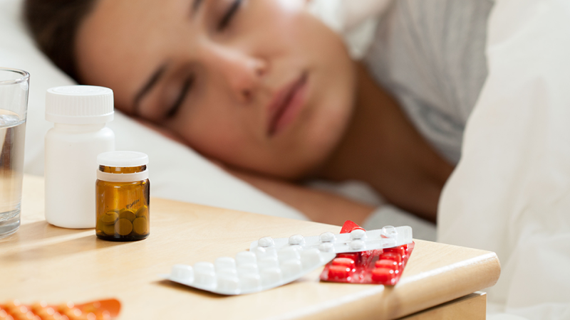 Mulher deitada na cama depois de tomar comprimidos para dormir