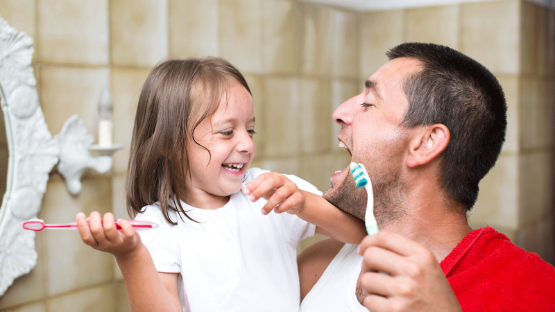 Pai e filha cuidam dos seus dentes