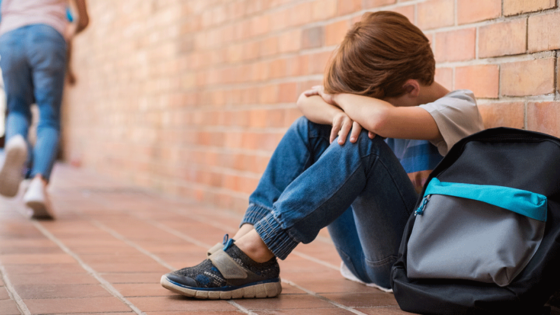 Criança triste por não se adaptar à nova escola