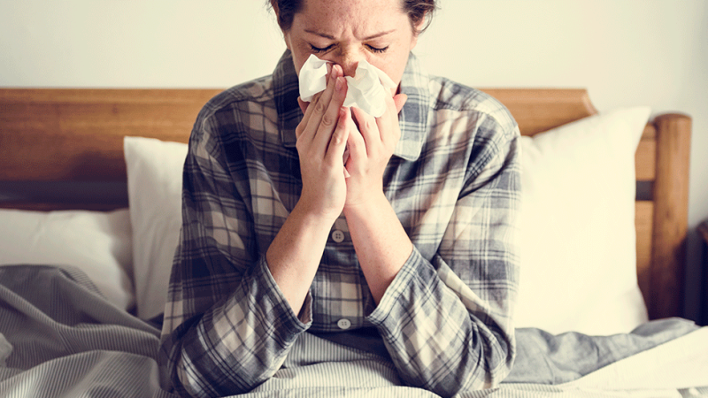 Mulher manifesta sintomas associados a gripes e constipações