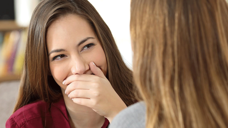 Mulher tapa boca com mão devido a mau hálito