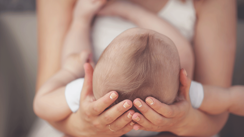 Mãe segura em cabeça de bebé com microcefalia