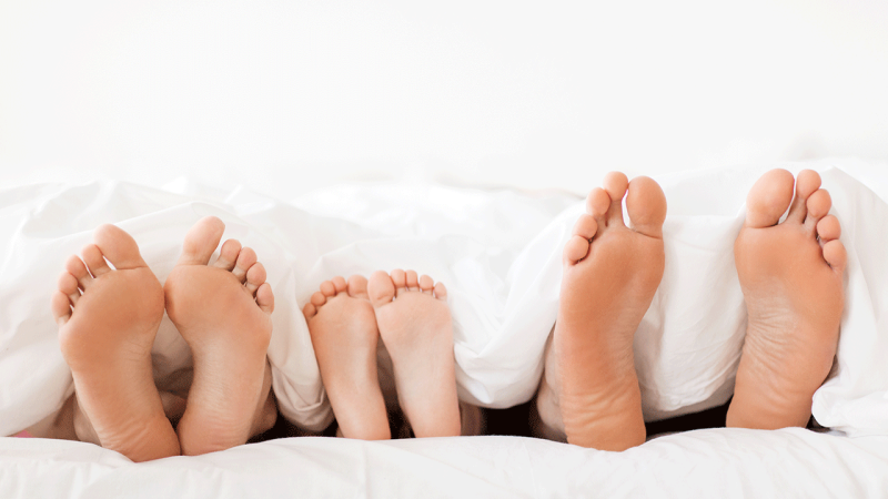 Família deitada na cama mostra anatomia do seu pé