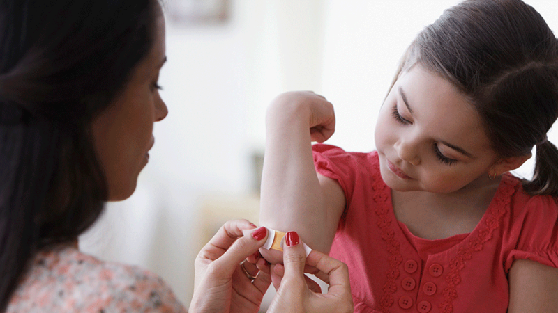 mãe ajuda a filha a tratar pequenas feridas corretamente