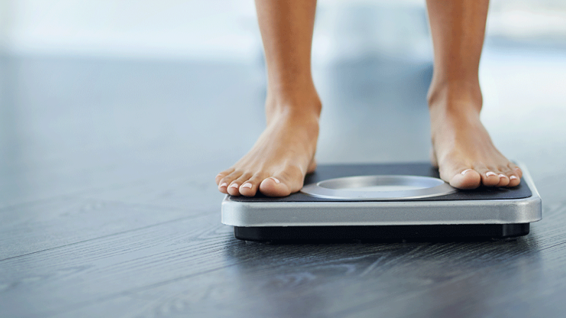Pessoa com dificuldades em perder peso pesa-se em balança