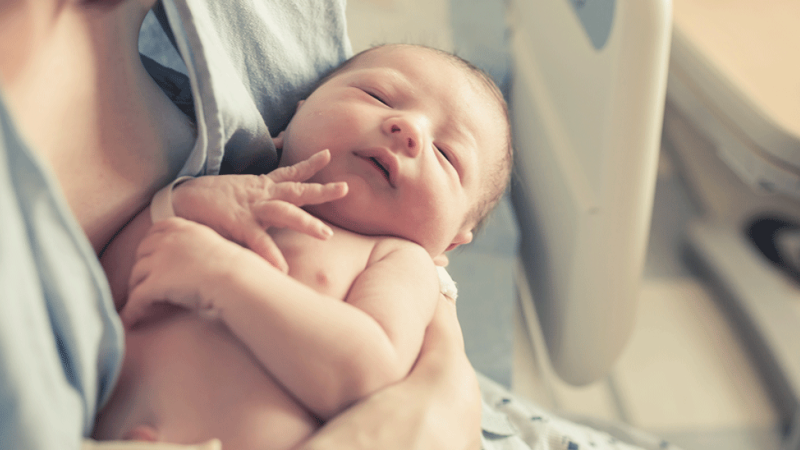 Mãe pega o seu bebé ao colo no pós-parto