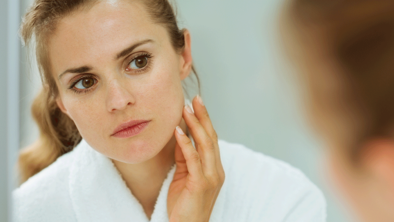 Mulher avalia rosto para diagnóstico de verrugas e cravos