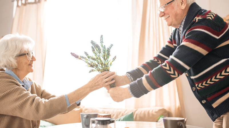Casal com mais de 65 anos segura flores