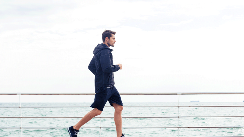 Homem informado sobre alimentação do desportista corre à beira da água