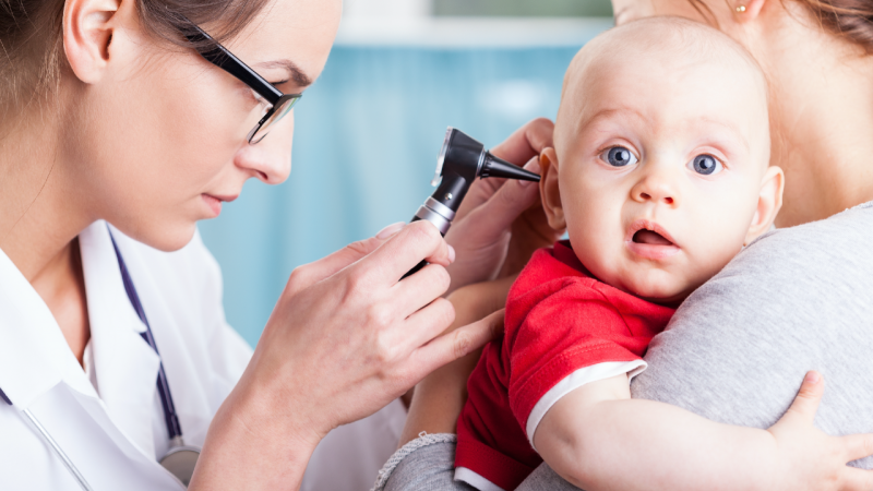 médica observa ouvido de criança com perda auditiva