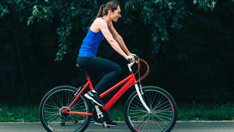 Mulher anda de bicicleta para estar em forma sem gastar dinheiro