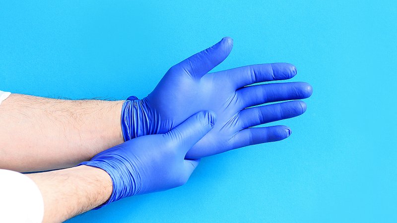 Close-up de mãos com luvas, que não diminuem risco de COVID-19