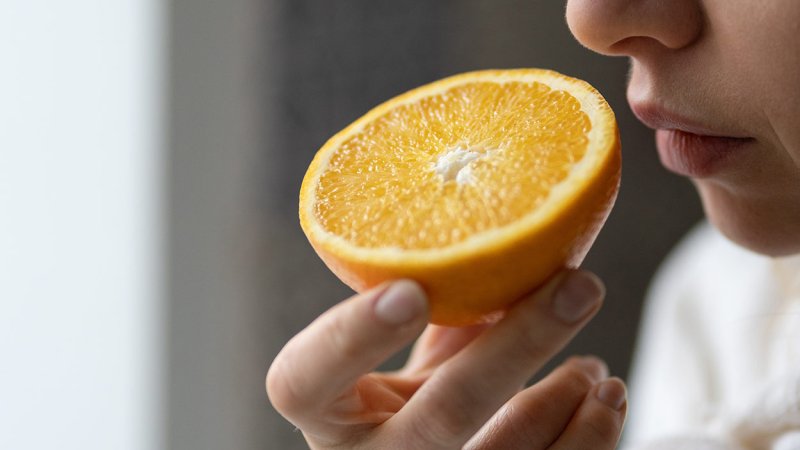 Pessoa cheira laranja para diagnosticar perda de paladar e de olfato