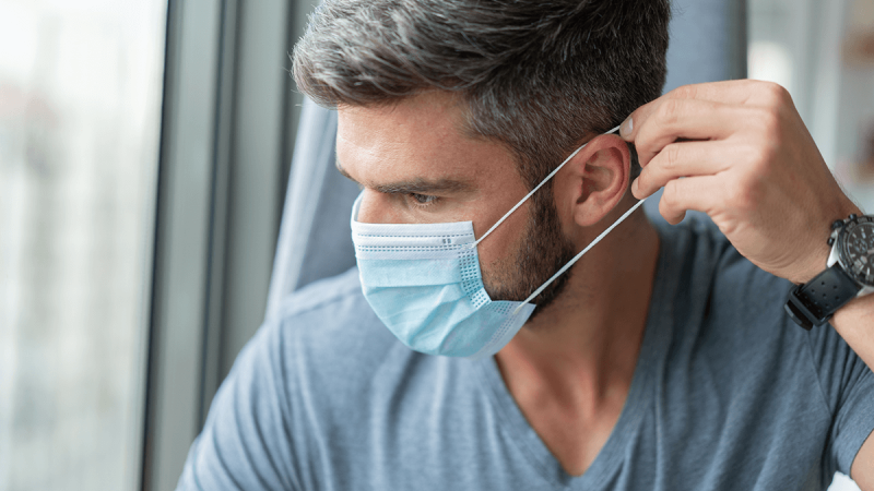 Homem coloca máscara para prevenir a COVID-19