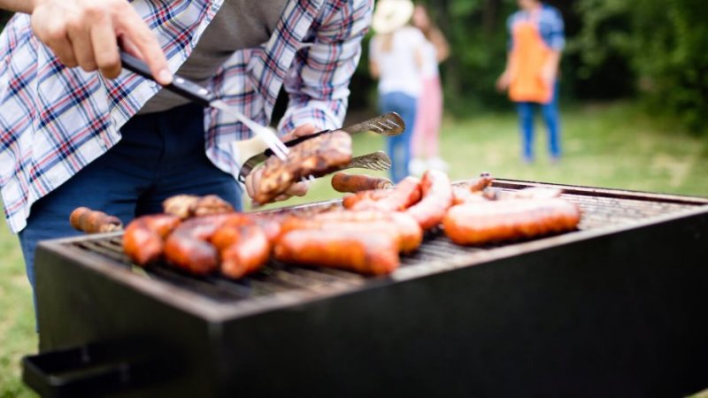 Homem a grelhar carne processada ao ar livre