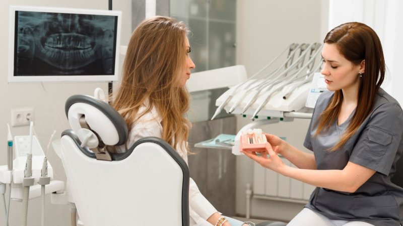 Mulher em consulta com médico dentista a ver soluções de implantes dentários