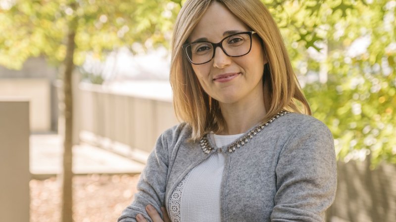 jovem mulher sorridentes e de braços cruzados no jardim