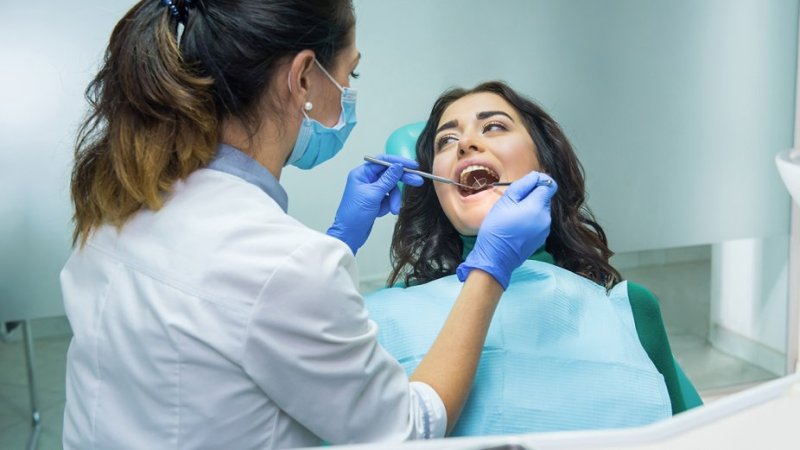 Médica dentista, em consulta, faz avaliação para despistar cancro oral na paciente