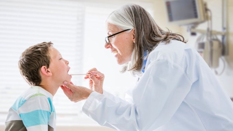 Médica examina criança para diagnóstico de candidíase oral (sapinhos)