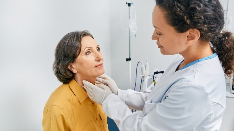 Médica examina paciente mulher para diagnóstico de doenças da tiroide