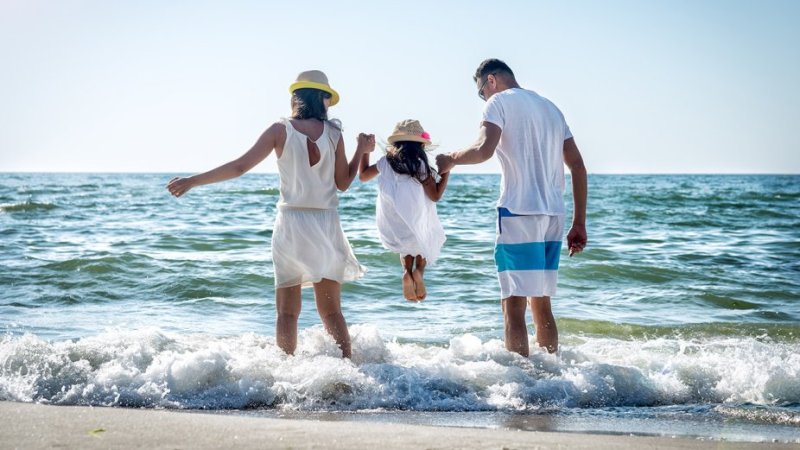 Pais e filha aproveitam as férias de verão na praia