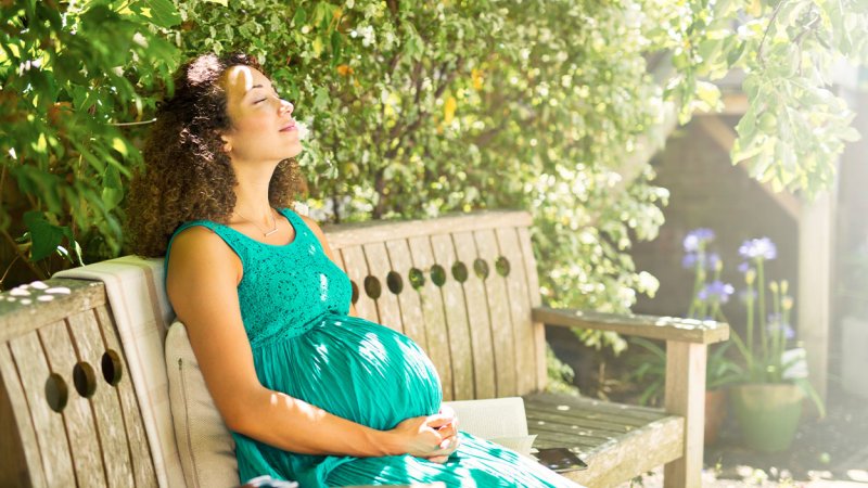 mulher grávida sentada num banco de jardim
