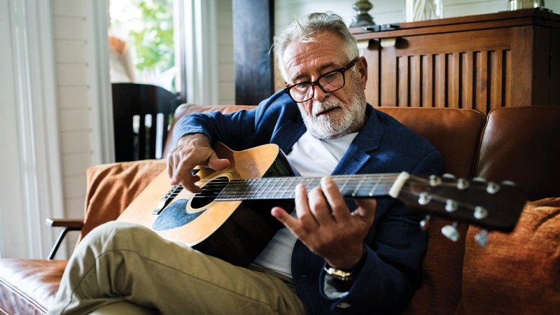 Homem idoso toca instrumento musical como estratégia para uma reforma saudável