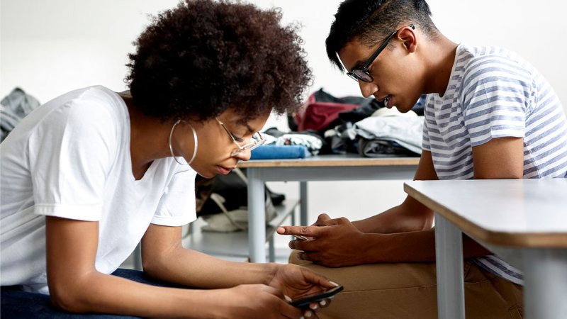 Pessoas utilizam telemóveis numa postura em que estão a olhar para baixo (pescoço SMS)