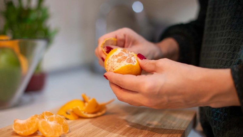 pessoa a descascar laranja numa bancada na cozinha