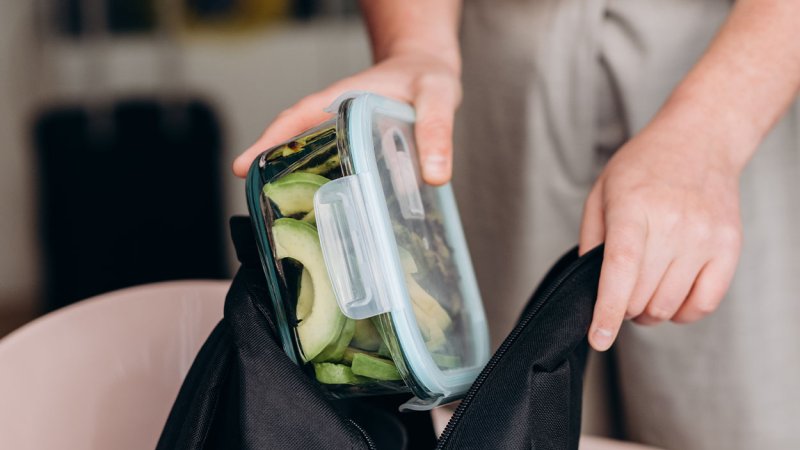 pessoa a arrumar uma marmita com snacks saudáveis numa mochila