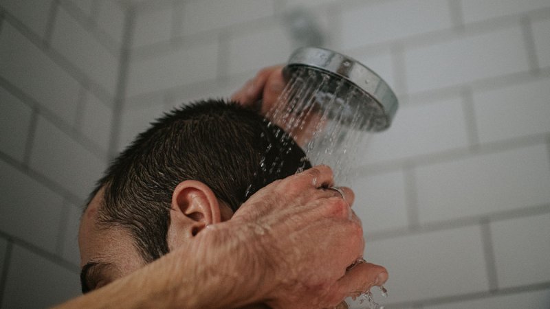 Homem toma duche quente.