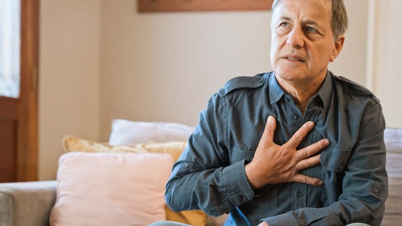 Homem com dor no peito leva a mão à zona do peito.