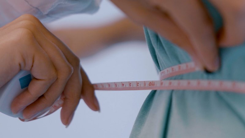 Nutricionista mete a cintura de doente.