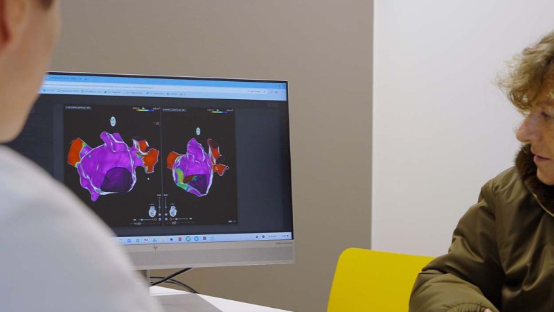 Médico e paciente analisam imagem de coração no computador.
