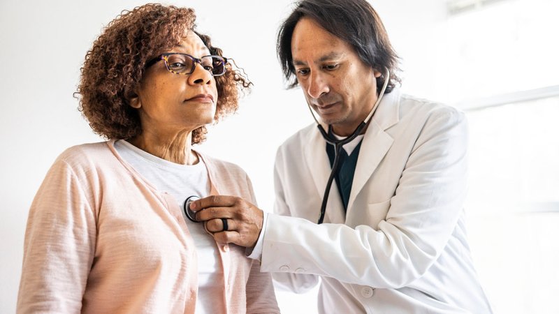 Mulher é auscultada por médico.