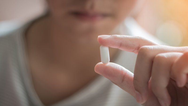 Pessoa toma comprimido de ibuprofeno