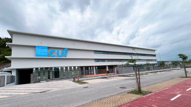 fachada do Hospital CUF Leiria com céu nublado e vista do parque de estacionamento exterior