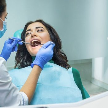 Médica dentista, em consulta, faz avaliação para despistar cancro oral na paciente