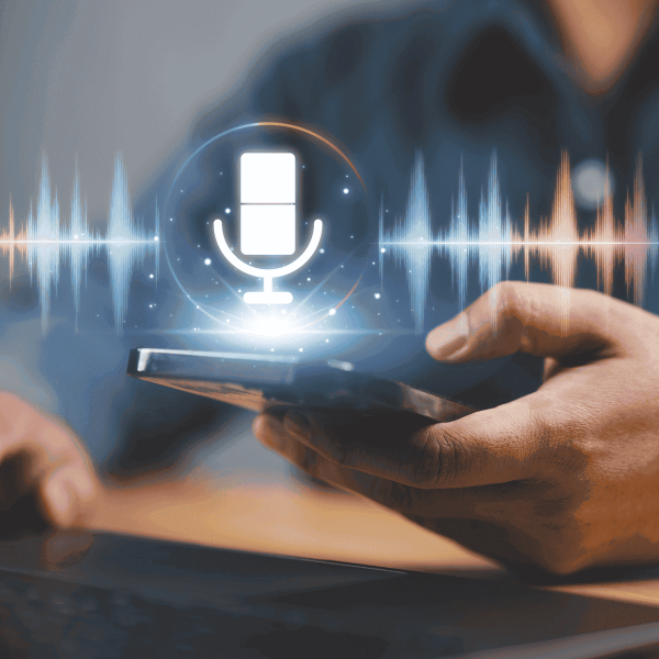Pessoa a segurar num telemóvel enquanto um ícone digital de microfone e ondas sonoras aparece acima do ecrã, simbolizando tecnologia de gravação ou reconhecimento de voz