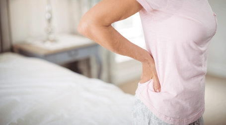 Indivíduo com dor nas costas, um dos sintomas do cancro