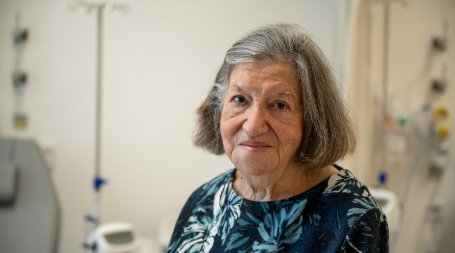 senhora idosa em ambiente hospitalar sentada a olhar de frente para a câmara